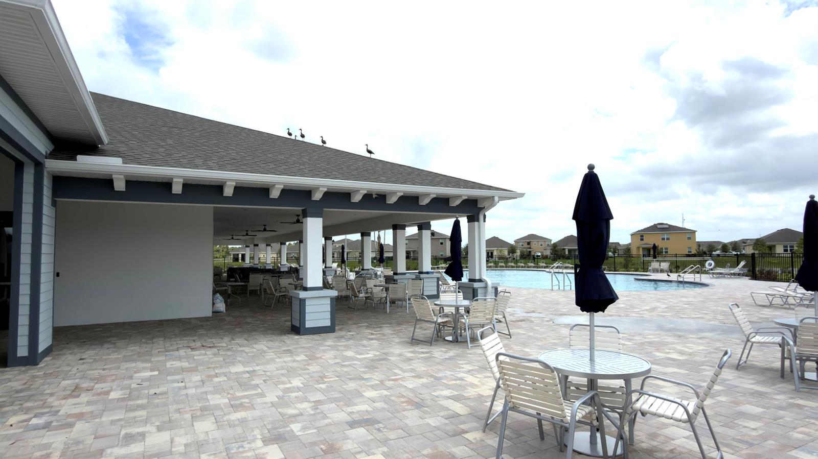 A covered patio with outdoor seating overlooks a swimming pool and residential homes — 9617 Potomac Drive, Fort Pierce FL 34945, FORT PIERCE, FL