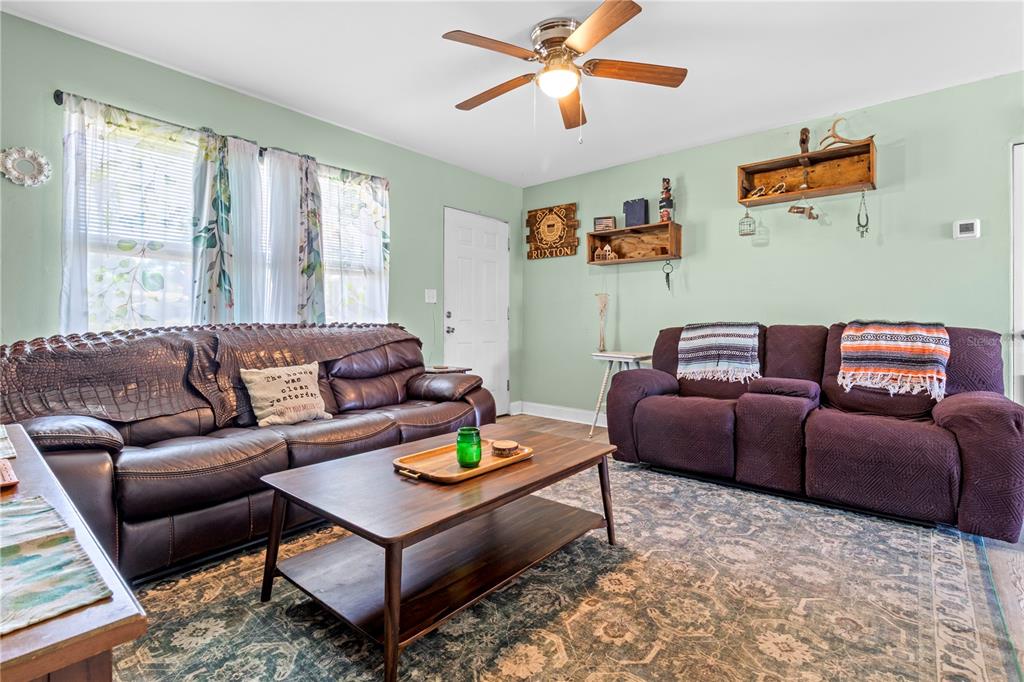 A living room features two leather sofas, a wooden coffee table, and light green walls — 5771 91ST AVENUE N, PINELLAS PARK, FL