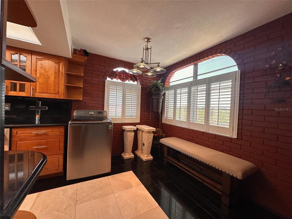 A kitchen area features a stainless steel washing machine, brick walls, and arched windows — 2699 SEVILLE BOULEVARD UNIT 701, CLEARWATER, FL