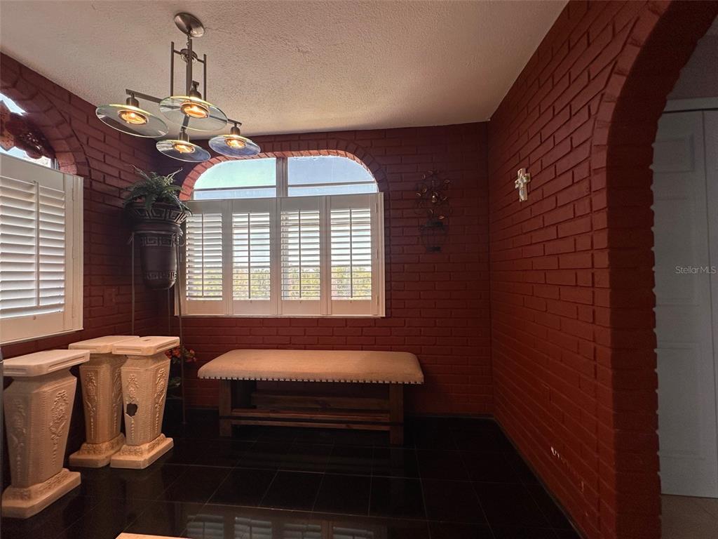 A room with red brick walls, black tile flooring, a bench, and an arched window — 2699 SEVILLE BOULEVARD UNIT 701, CLEARWATER, FL