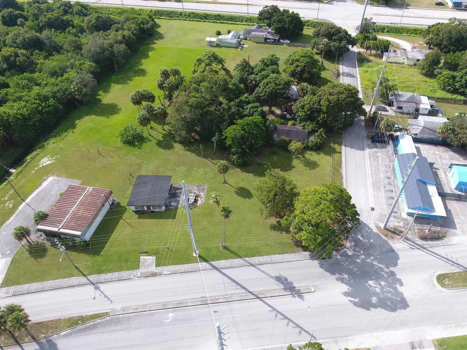 An aerial view shows a grassy lot with two small houses and surrounding trees — 3805 Okeechobee Road, Fort Pierce FL 34947, FORT PIERCE, FL