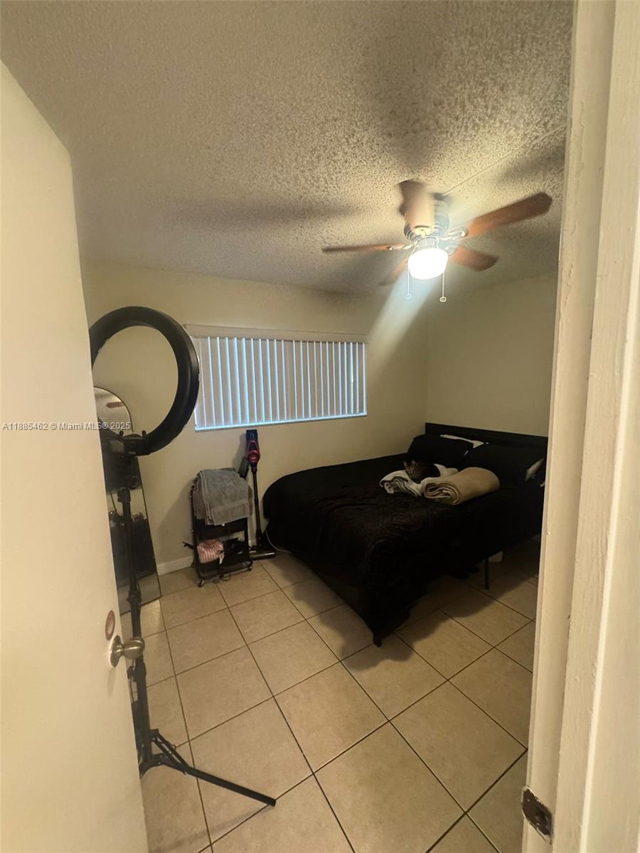 A bedroom features a bed with black bedding, a ceiling fan, and tiled flooring — 6900 SW 39th St # 106J, Davie FL 33314, DAVIE, FL