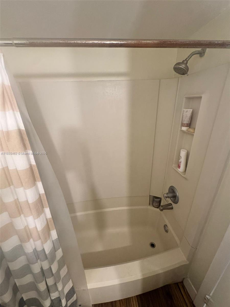 A beige bathtub and shower combination features a built-in niche and a shower curtain — 6900 SW 39th St # 106J, Davie FL 33314, DAVIE, FL