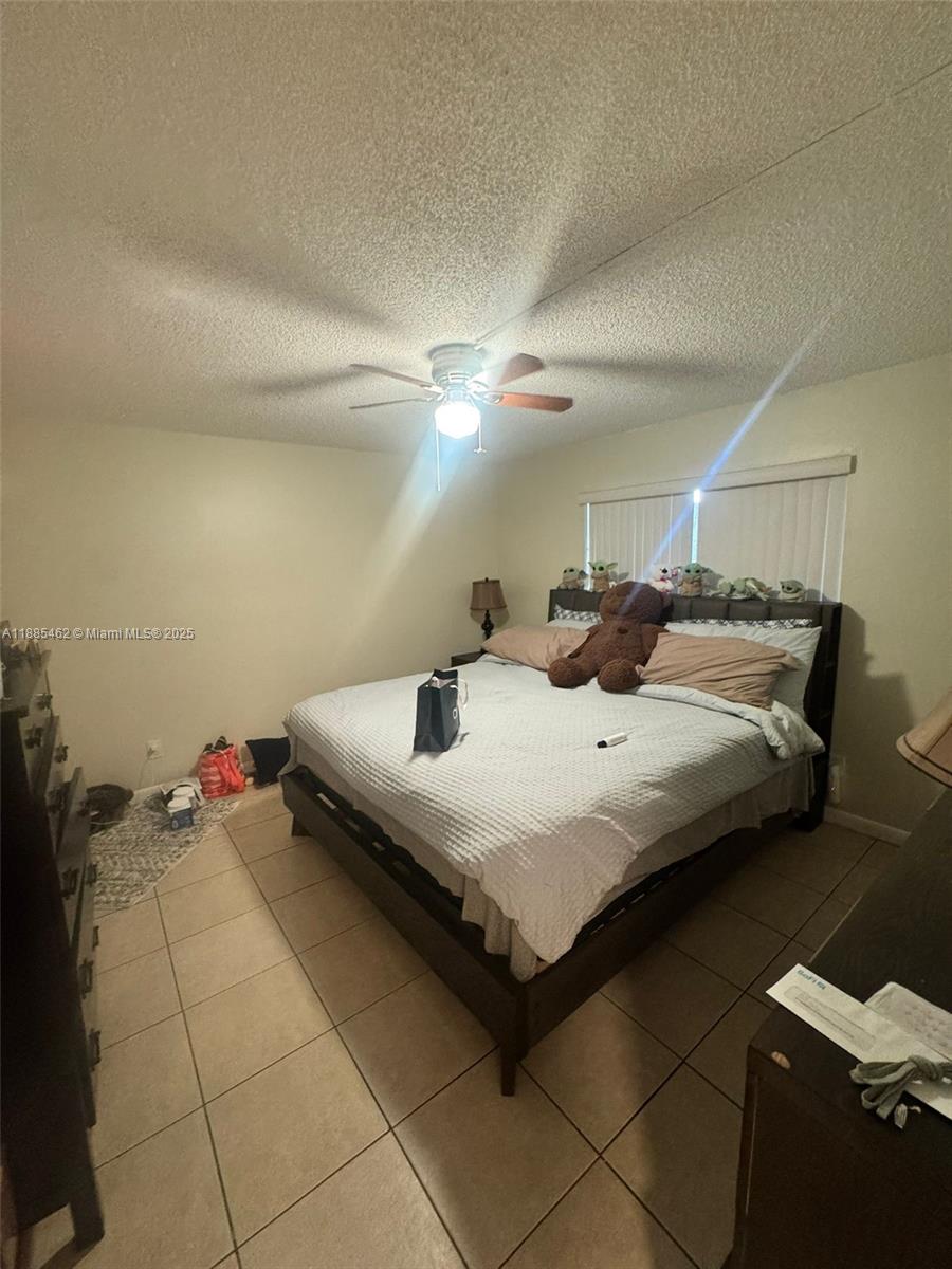 A bedroom features a large bed, tiled flooring, a ceiling fan, and a dresser — 6900 SW 39th St # 106J, Davie FL 33314, DAVIE, FL