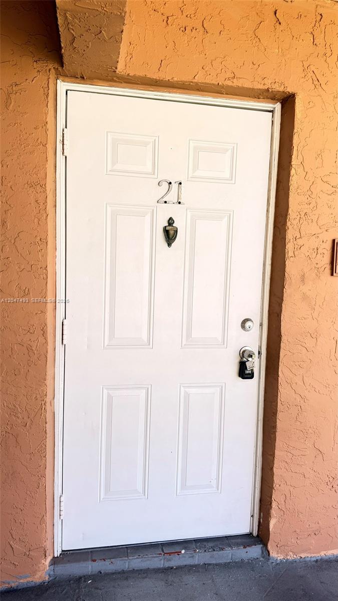 A white front door with the number 21 is set into an orange stucco wall — 978 SW 10th Dr # 21, Pompano Beach FL 33060, POMPANO BEACH, FL