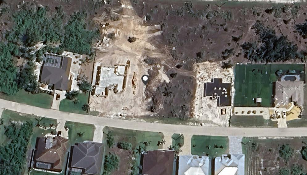 This aerial view shows a residential street with two houses under construction on cleared lots — 15357 TAURUS CIRCLE, PORT CHARLOTTE, FL