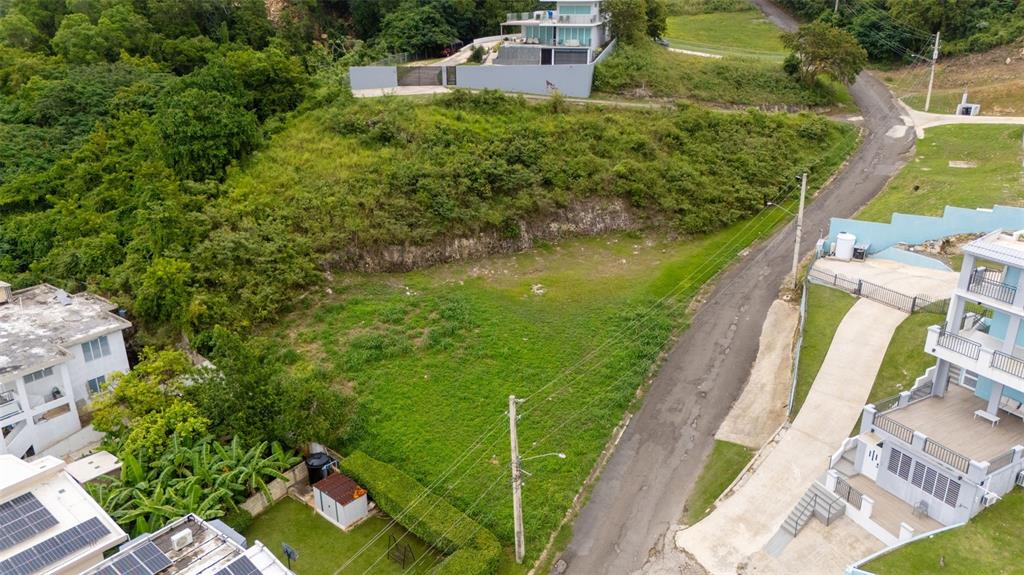 An aerial view shows a vacant, grassy residential lot situated between two multi-story houses — CARR. 107 INT.BO.BORINQUEN, AGUADILLA, PR