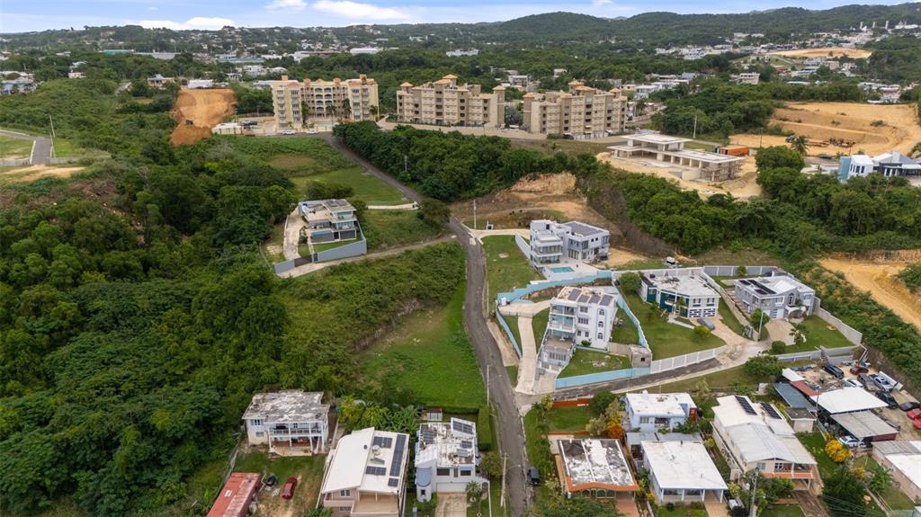 An aerial view shows a residential neighborhood with houses, apartment buildings, and surrounding green hills — CARR. 107 INT.BO.BORINQUEN, AGUADILLA, PR