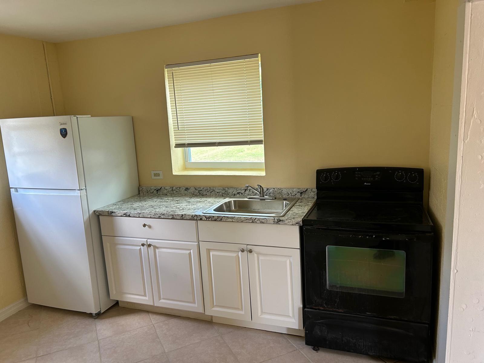 A kitchen with white cabinets, granite countertops, a white refrigerator, and a black stove — 371 Banyan Avenue, Pahokee FL 33476, PAHOKEE, FL