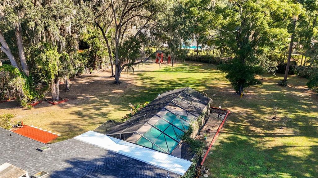 An aerial view of a backyard featuring a screened-in pool and a large grassy lawn — 3811 SW 82ND STREET, GAINESVILLE, FL