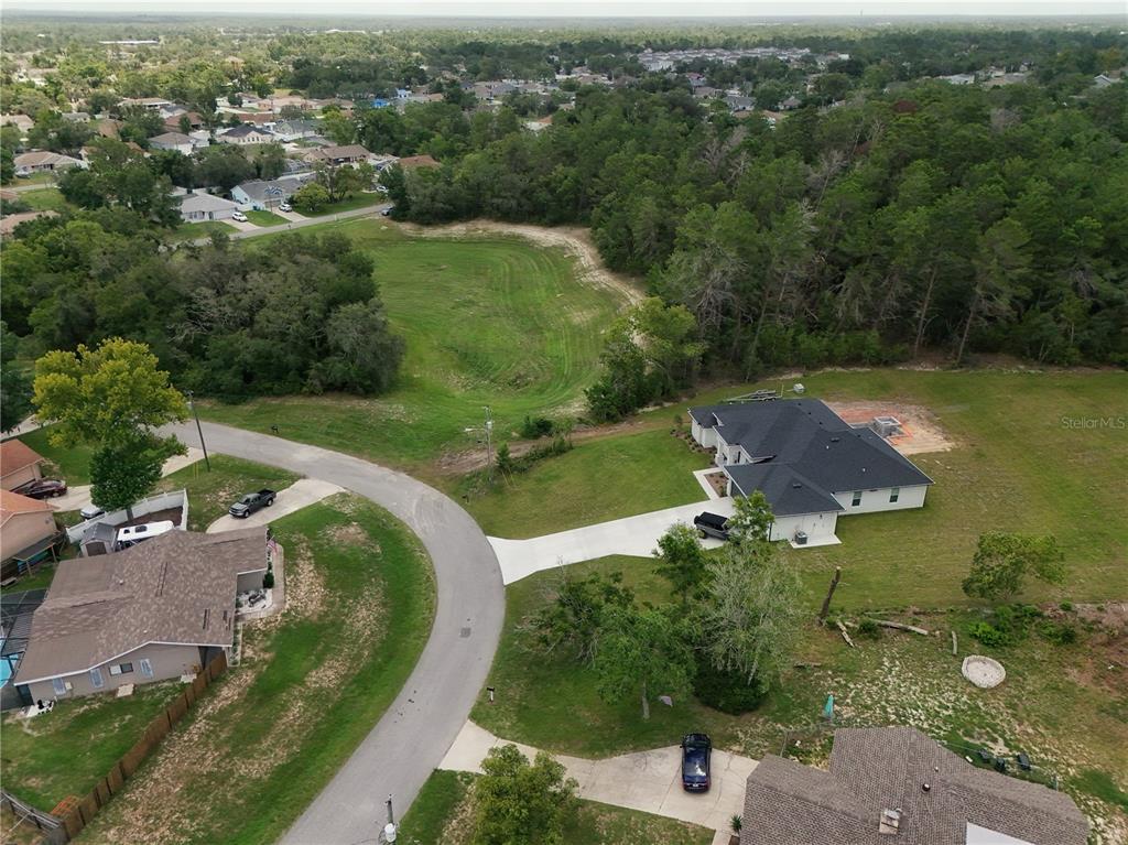 An aerial view shows a suburban neighborhood with a large house, driveway, and grassy lot — 0 FAYSON LANE, SPRING HILL, FL
