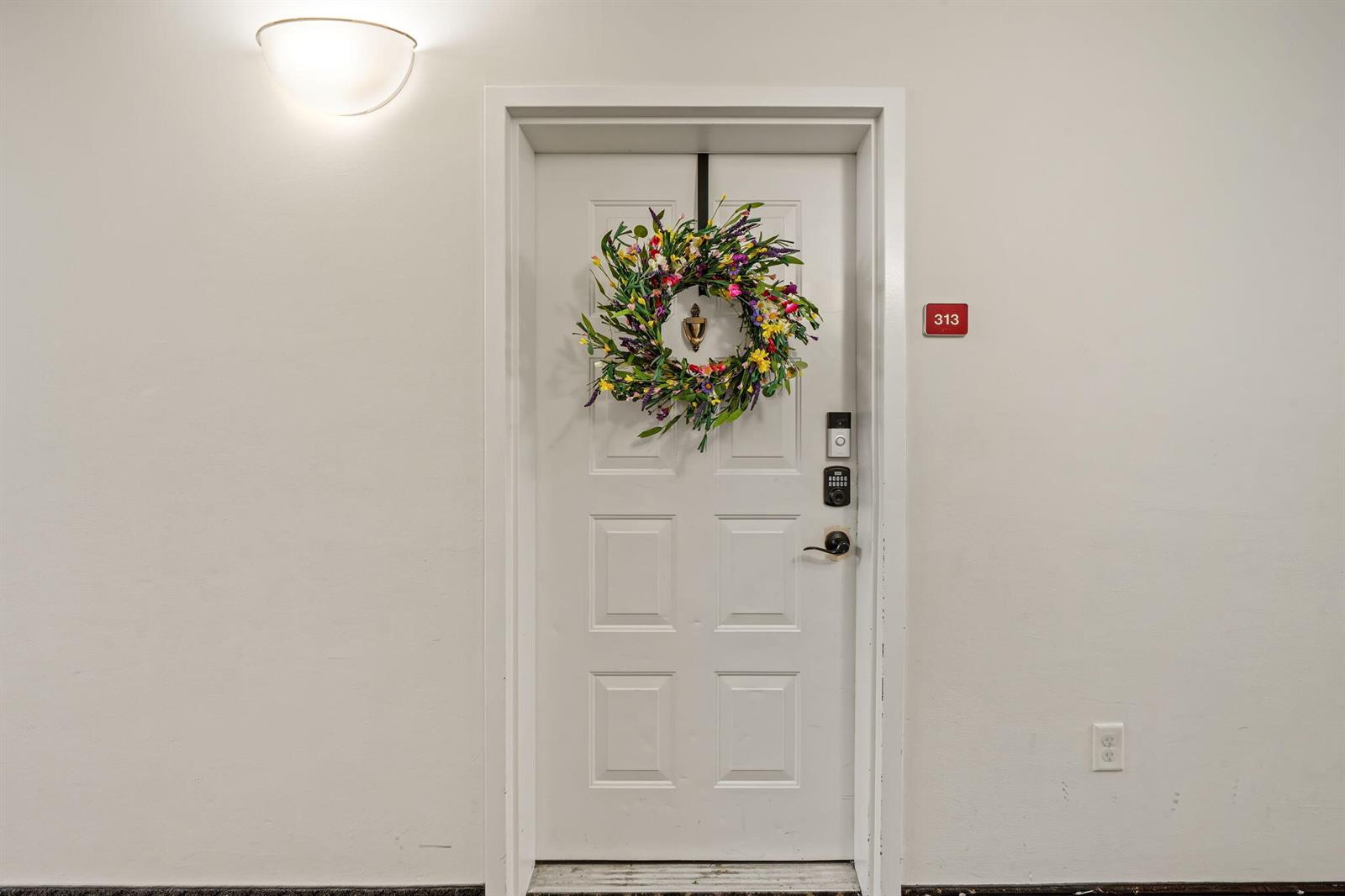 A white apartment door with a floral wreath and a red unit number sign — 1203 Town Center Drive # 313, Jupiter FL 33458, JUPITER, FL