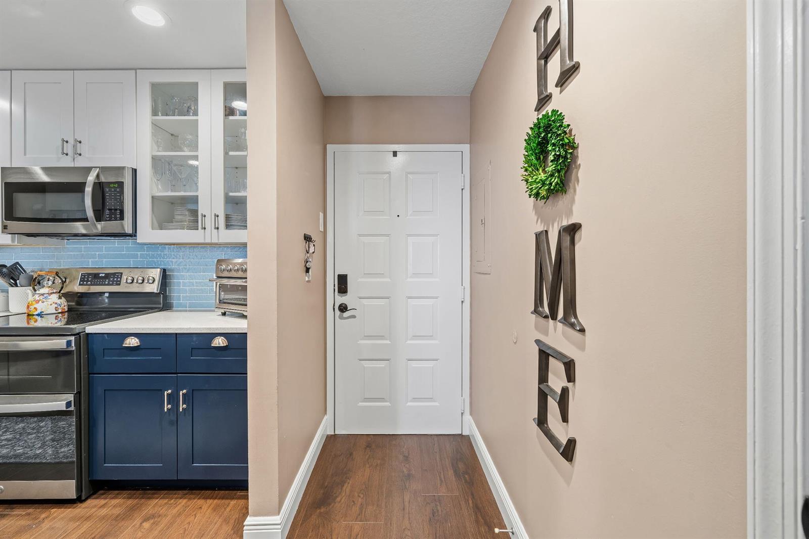 A kitchen entrance features blue cabinets, a white door, and wall-mounted metal letters — 1203 Town Center Drive # 313, Jupiter FL 33458, JUPITER, FL