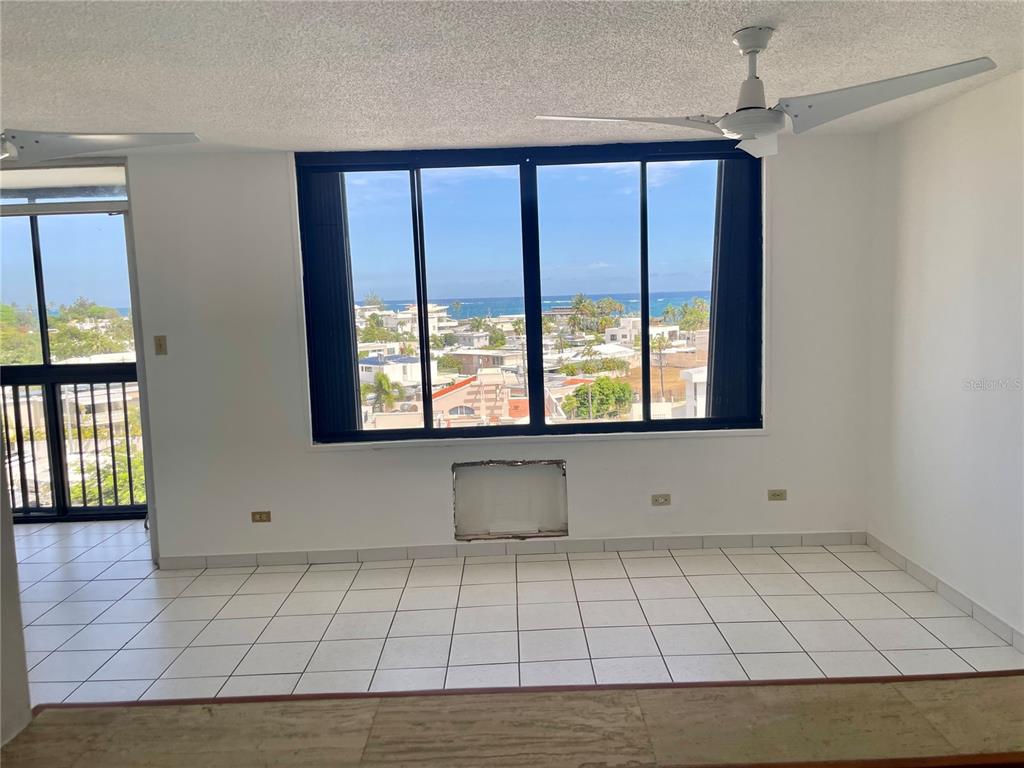 A room with white tiled floors, a ceiling fan, and a large window overlooking the ocean — 1 INGA STREET UNIT 6F, SAN JUAN, PR