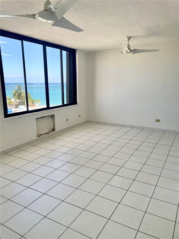 An empty room with white tiled floors, two ceiling fans, and a large ocean-view window — 1 INGA STREET UNIT 6F, SAN JUAN, PR