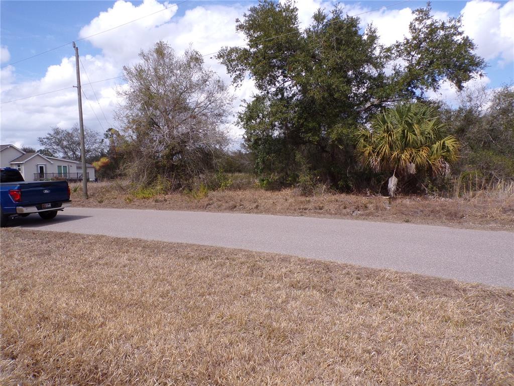 A blue pickup truck is parked on a paved road next to a vacant lot — 208 and 214 ROSE CIRCLE, PUNTA GORDA, FL