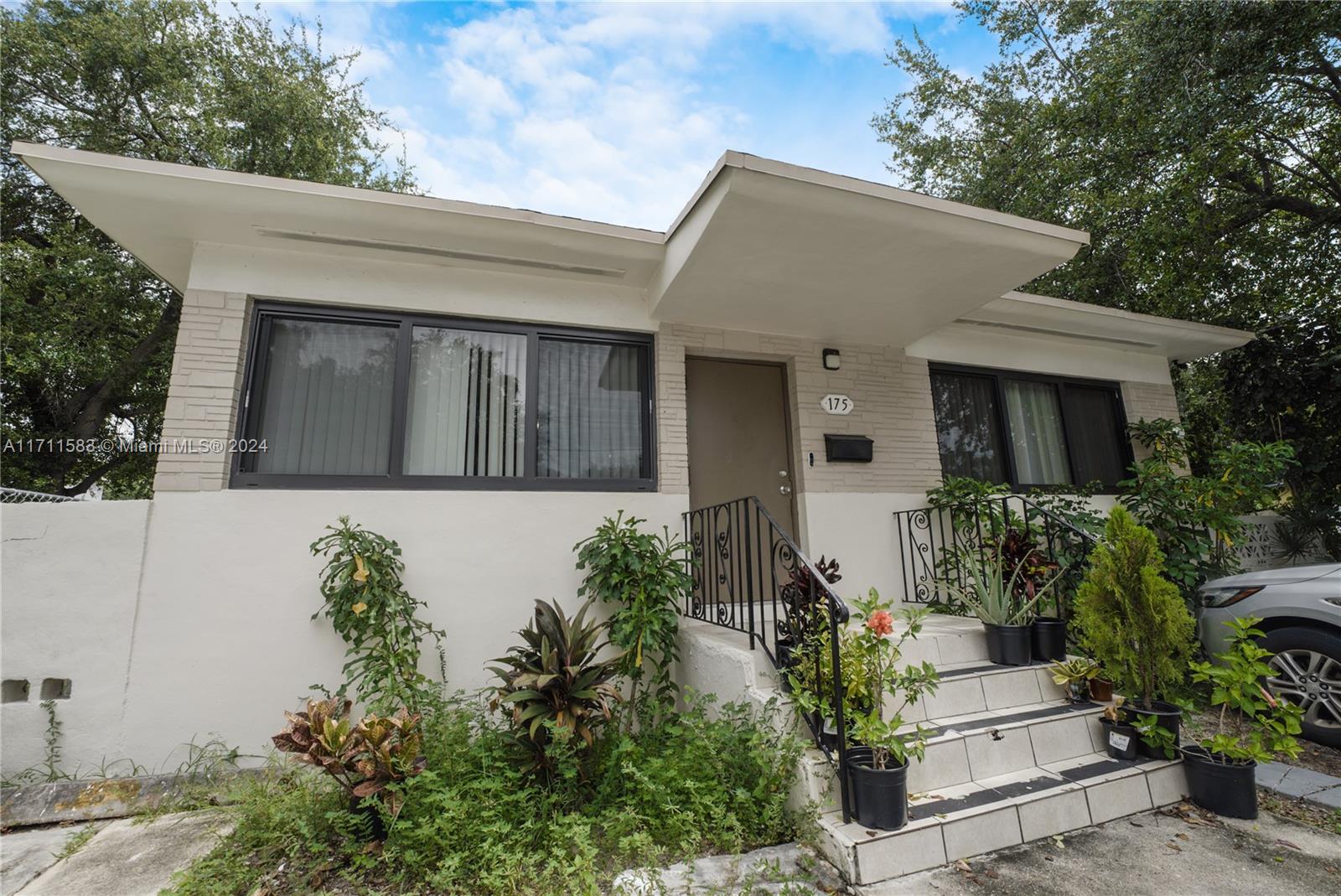 The exterior of a single-story house features a flat roof, white walls, and front steps — 175 NW 68th St, Miami FL 33150, MIAMI, FL