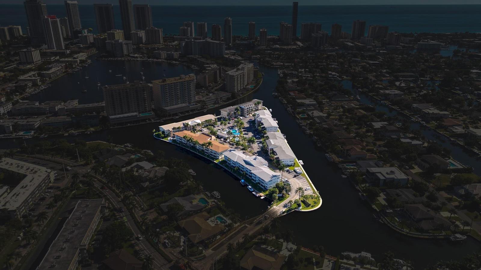 Aerial view of a triangular apartment complex surrounded by water in a coastal city — 450 Paradise Isle Boulevard, Hallandale Beach FL 33009, HALLANDALE BEACH, FL