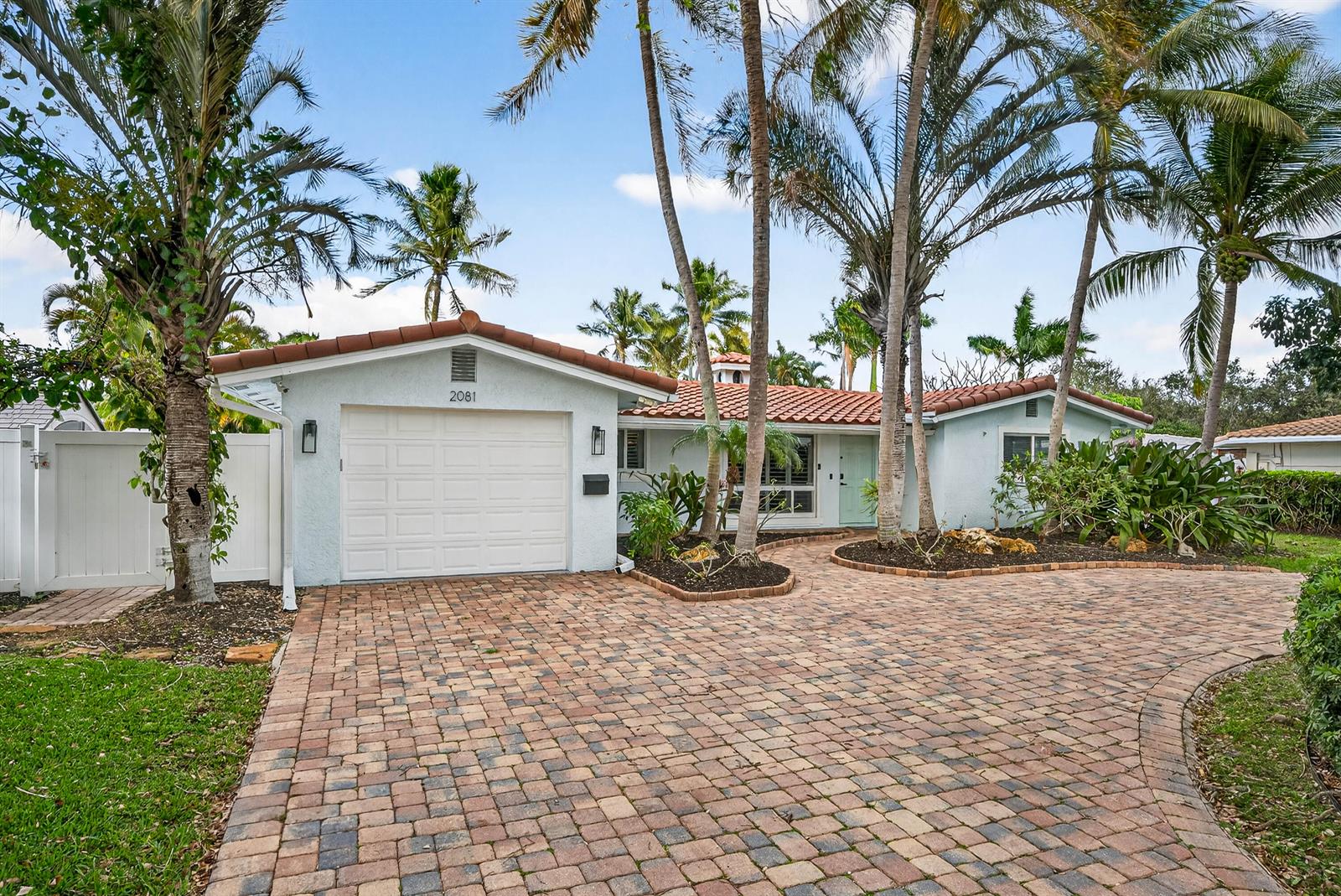 A single-story house with a white garage, tiled roof, and a brick-paved driveway — 2081 NE 25th Street, Lighthouse Point FL 33064, LIGHTHOUSE POINT, FL