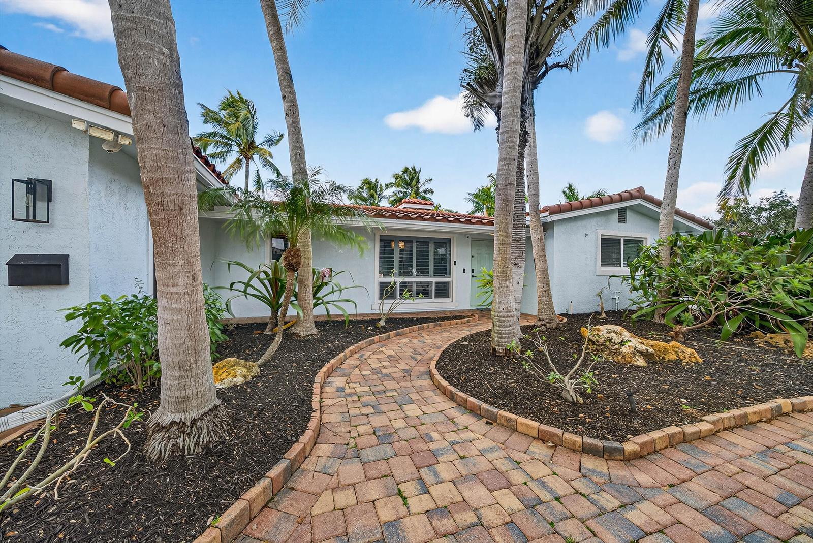 A paved walkway leads to the front entrance of a single-story house with palm trees — 2081 NE 25th Street, Lighthouse Point FL 33064, LIGHTHOUSE POINT, FL