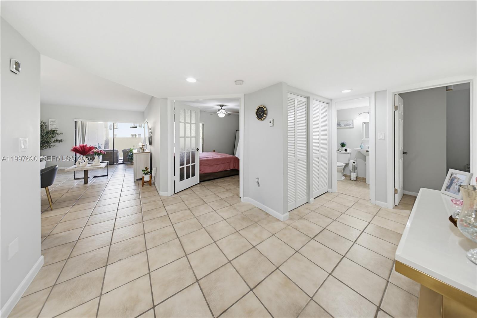 A tiled living area leads to a bedroom with French doors and an adjacent bathroom — 12984 SW 88th Ln # B104, Miami FL 33186, MIAMI, FL