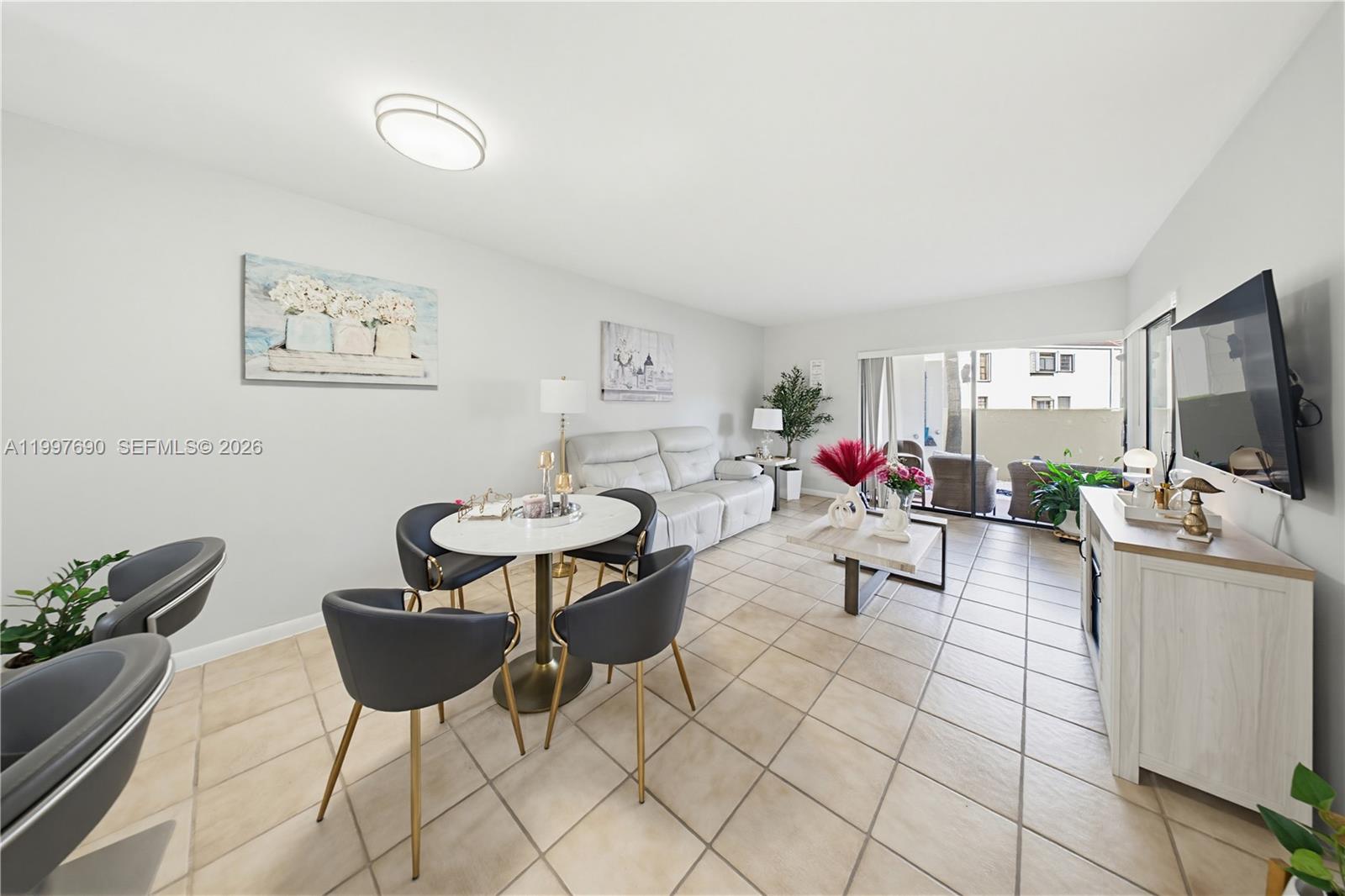 A living and dining area features tile flooring, a white sofa, and a glass sliding door — 12984 SW 88th Ln # B104, Miami FL 33186, MIAMI, FL