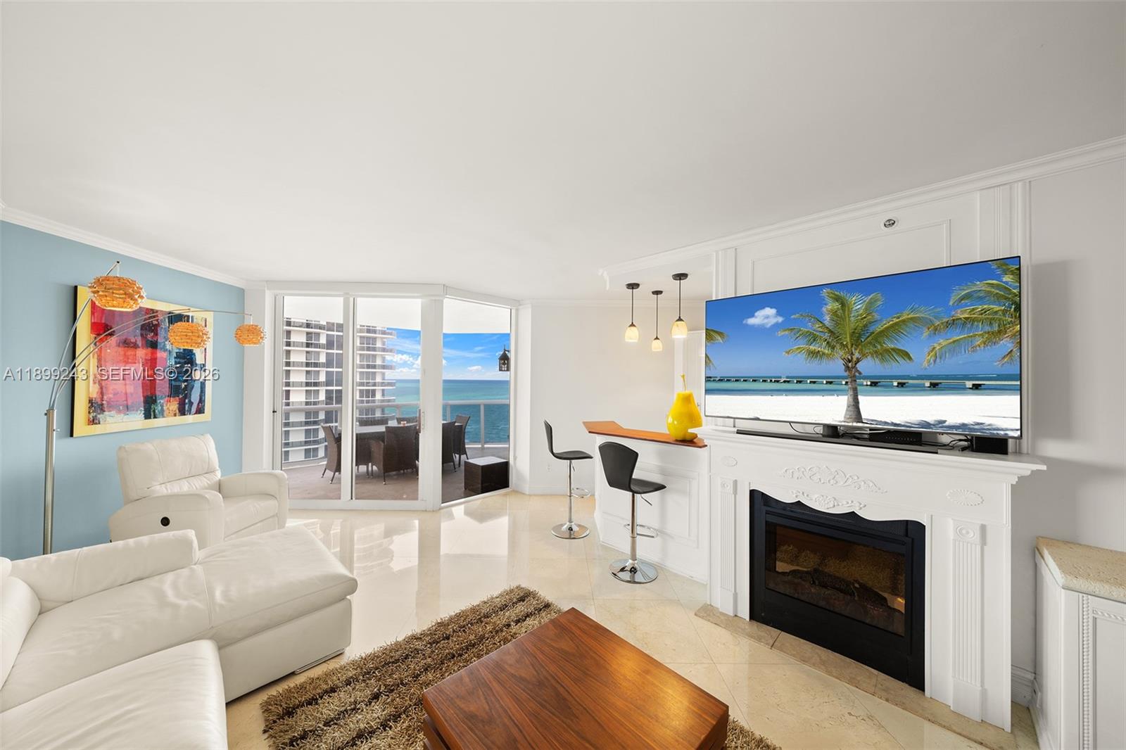 A living room features a fireplace, a bar area, white furniture, and a balcony view — 4775 Collins Ave # 1708, Miami Beach FL 33140, MIAMI BEACH, FL