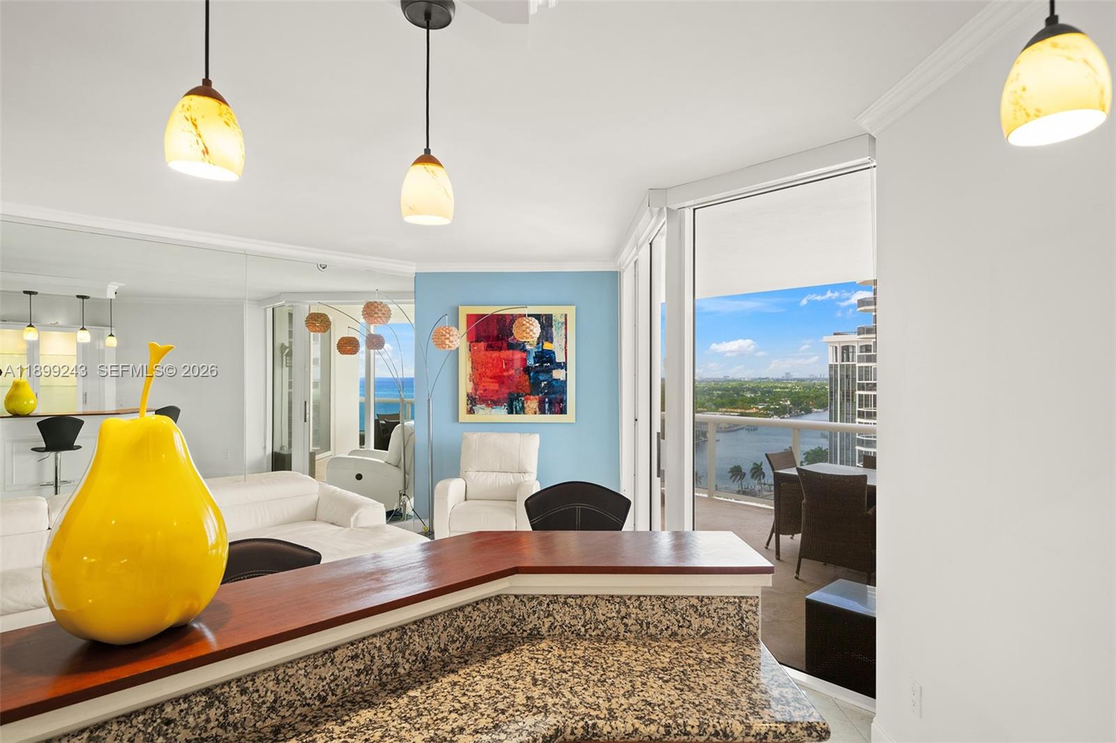 A kitchen counter overlooks a living area with a balcony and water view — 4775 Collins Ave # 1708, Miami Beach FL 33140, MIAMI BEACH, FL