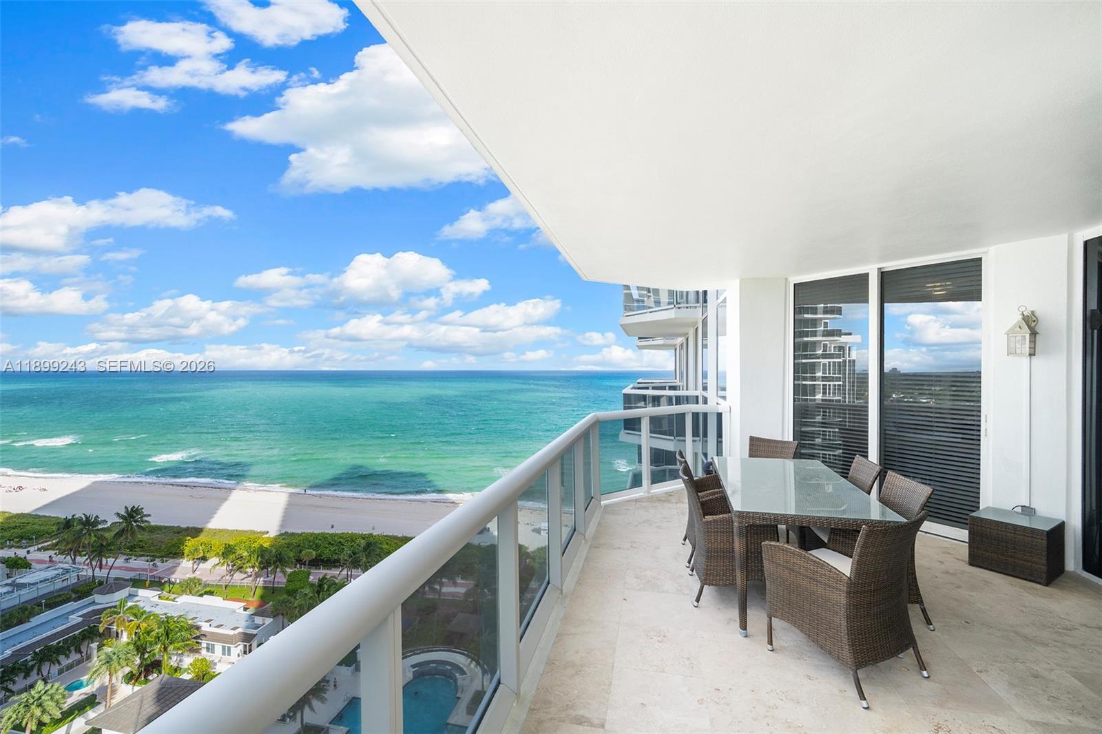 A balcony with outdoor dining furniture overlooks the ocean and beach — 4775 Collins Ave # 1708, Miami Beach FL 33140, MIAMI BEACH, FL