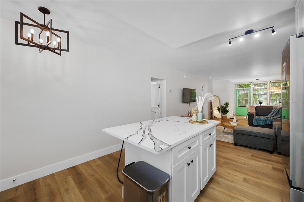 A kitchen island with a white marble-patterned countertop sits in an open-concept living space — 1433 S BELCHER ROAD UNIT F9, CLEARWATER, FL