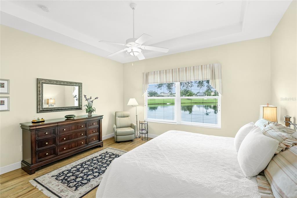 A bedroom features a bed, a wooden dresser with a mirror, and a window view — 3631 SUMMERWIND CIRCLE, BRADENTON, FL