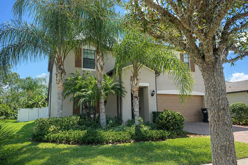 A two-story stucco house features a two-car garage, palm trees, and a landscaped front yard — 2515 SHERMAN OAK DRIVE, NORTH PORT, FL
