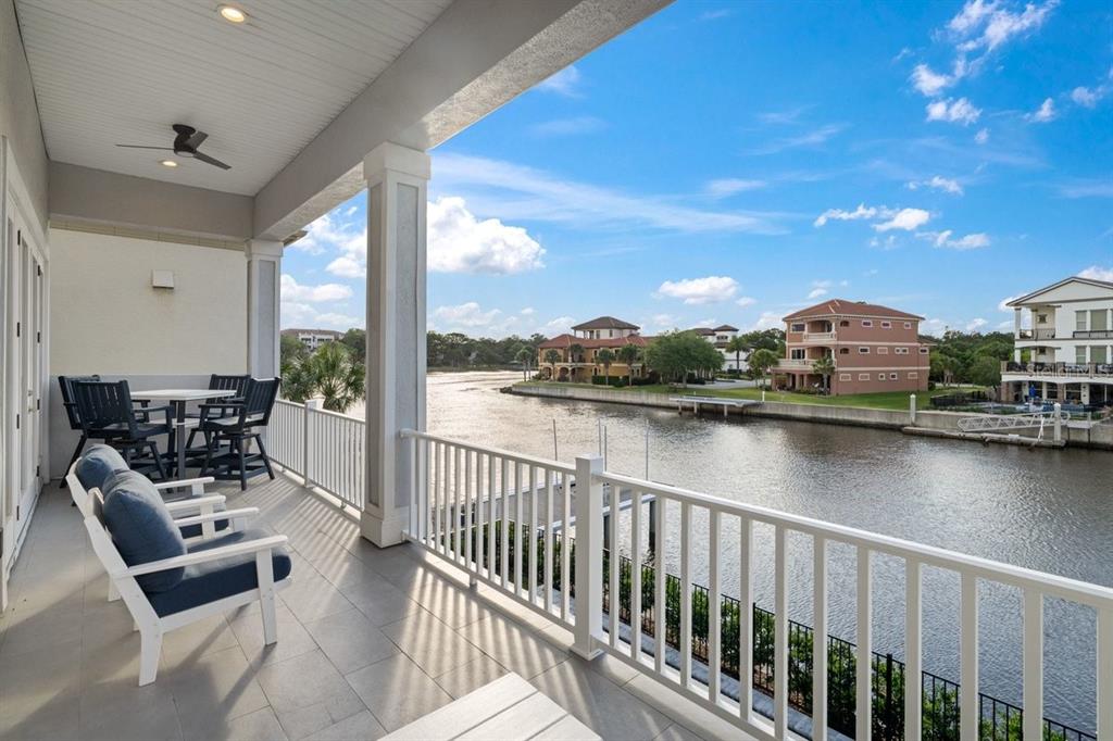 A covered balcony with outdoor seating overlooks a canal and neighboring houses — 18 SPINAKER CIRCLE, PALM COAST, FL