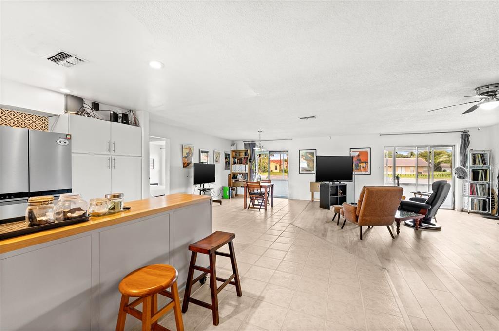An open-concept living area features a kitchen island, tile flooring, and a dining space — 10760 WILDERNESS COURT, ORLANDO, FL