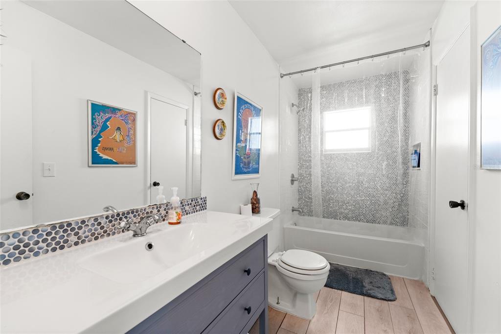 A bathroom features a blue vanity, a white countertop, and a tiled shower-tub combination — 10760 WILDERNESS COURT, ORLANDO, FL