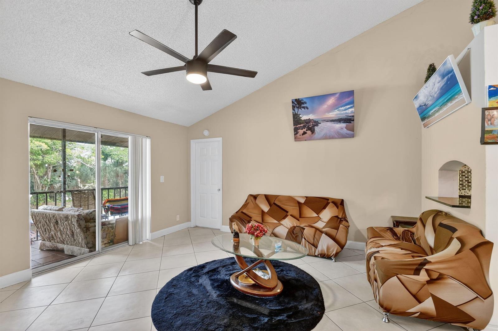 A living room with tile floors, a ceiling fan, and a sliding door to a balcony — 4191 S 57th Avenue G Avenue, FL 33463, FL