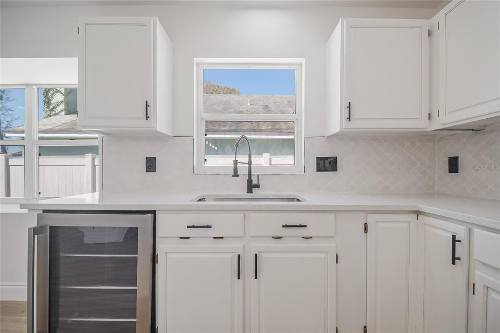 A kitchen features white cabinets, a stainless steel wine cooler, and a window above the sink — 808 WHITE IVEY COURT, APOPKA, FL