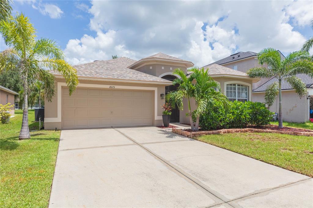A single-story house with a beige stucco exterior, a two-car garage, and palm trees — 1615 BONITA BLUFF COURT, RUSKIN, FL