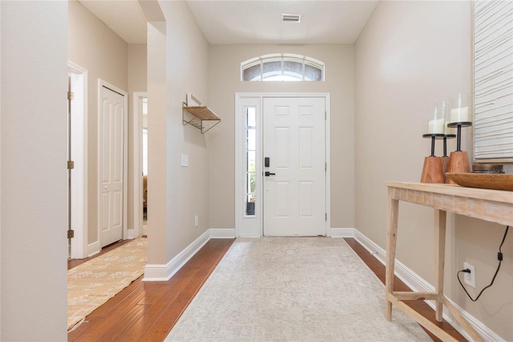 A bright entryway features a white front door, wood flooring, and a console table — 1615 BONITA BLUFF COURT, RUSKIN, FL