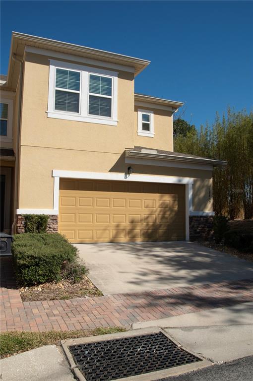 A two-story tan stucco townhouse features a two-car garage and a paved driveway — 17459 CHATEAU PINE WAY, CLERMONT, FL