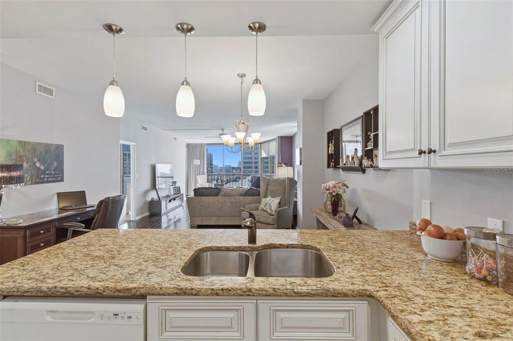 A kitchen island with a double sink overlooks an open-concept living area with city views — 1 BEACH DRIVE SE UNIT 1109, ST PETERSBURG, FL