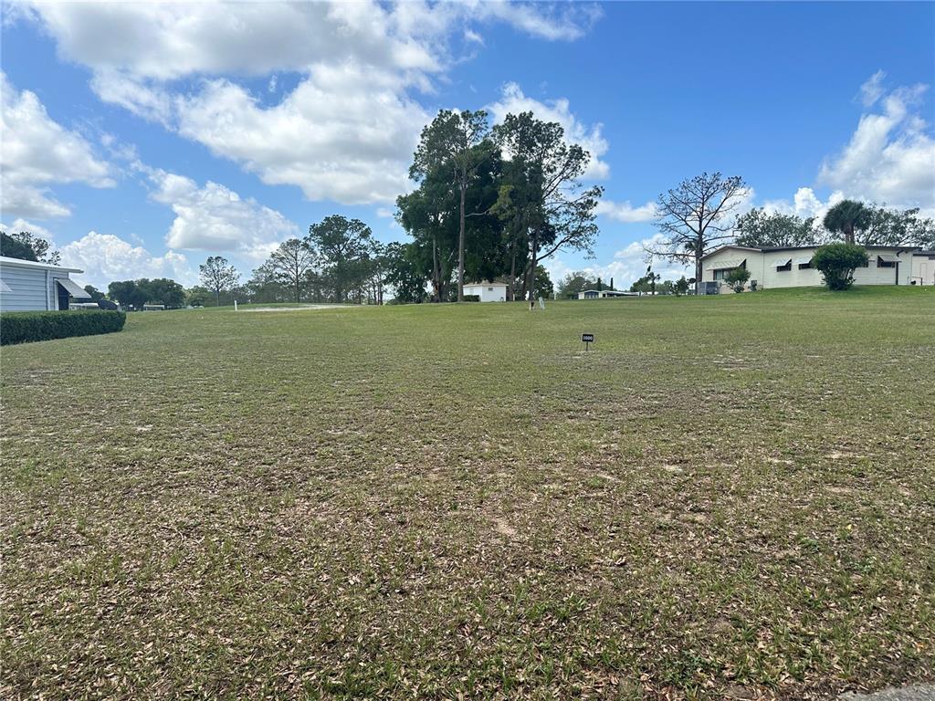 A grassy, vacant residential lot under a blue sky with scattered clouds — 2534 PUTTER ROAD UNIT 1600, ZELLWOOD, FL