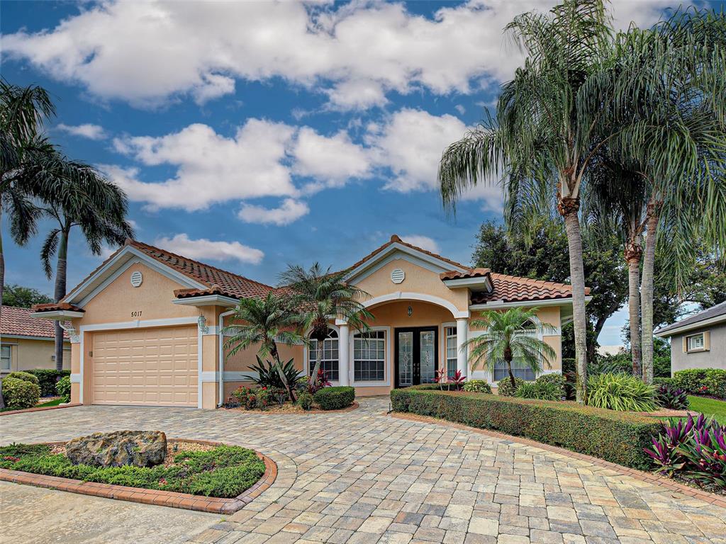 A single-story house with a paved driveway, palm trees, and a two-car garage — 5017 BELLA TERRA DRIVE, VENICE, FL
