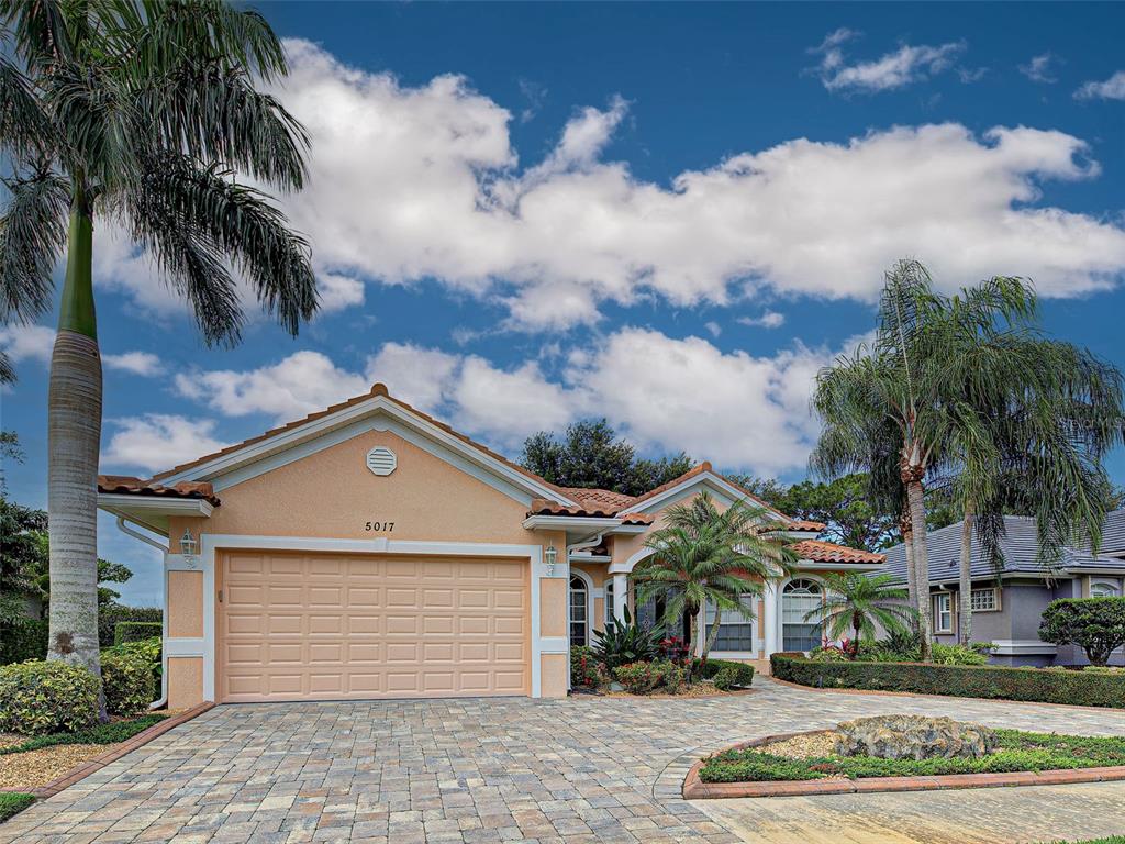 A single-story house with a tan stucco exterior, a two-car garage, and a paved driveway — 5017 BELLA TERRA DRIVE, VENICE, FL