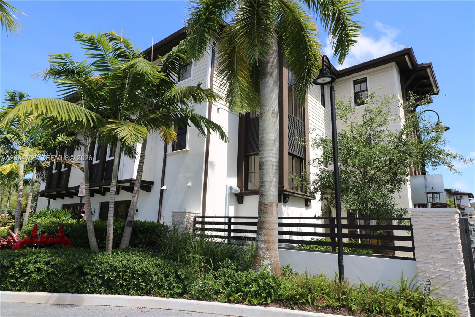 A multi-story building with white siding, dark trim, and palm trees in front — 7504 SW 100th St, Pinecrest FL 33156, PINECREST, FL