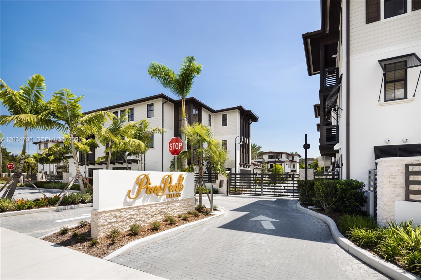 An exterior view of the Pine Park Villas gated entrance with palm trees and buildings — 7504 SW 100th St, Pinecrest FL 33156, PINECREST, FL