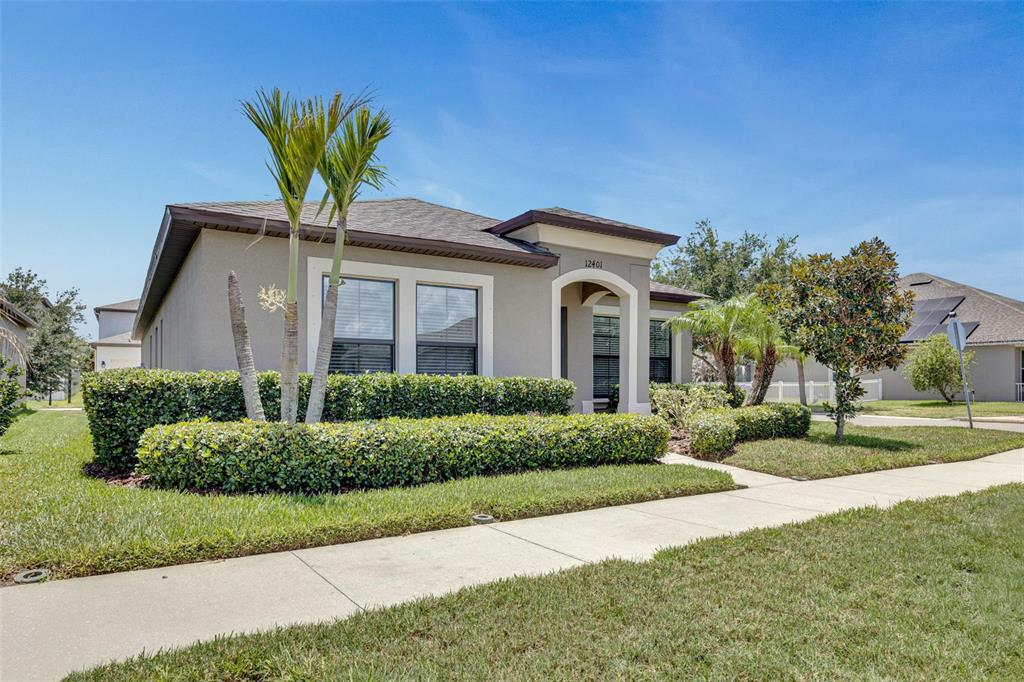 A single-story house with a beige exterior, a covered entryway, and manicured hedges — 12401 STREAMBED DRIVE, RIVERVIEW, FL