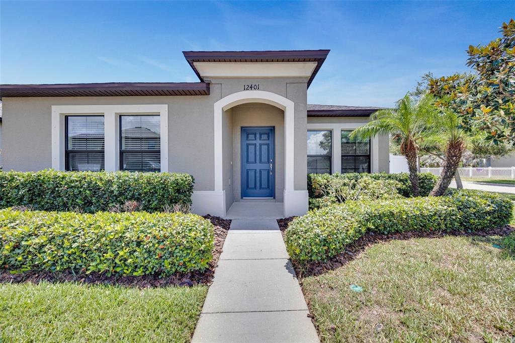 The exterior of a single-story house features a blue front door and manicured hedges — 12401 STREAMBED DRIVE, RIVERVIEW, FL