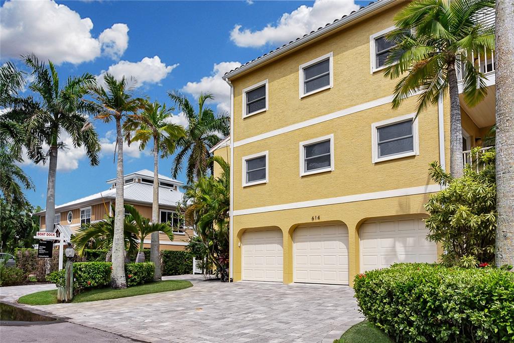 A swimming pool sits in a backyard overlooking a canal with a boat and house — 614 NORTON STREET, LONGBOAT KEY, FL