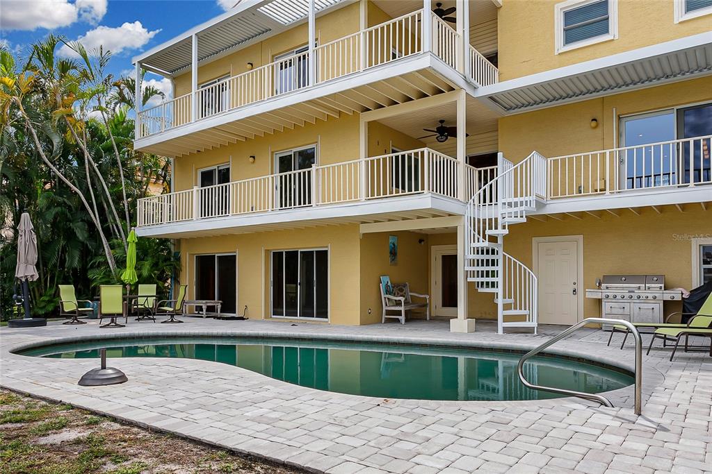A three-story yellow house features white balconies, a spiral staircase, and a backyard swimming pool — 614 NORTON STREET, LONGBOAT KEY, FL
